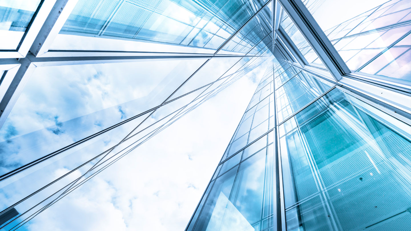 Looking up at a tall glass building toward blue sky