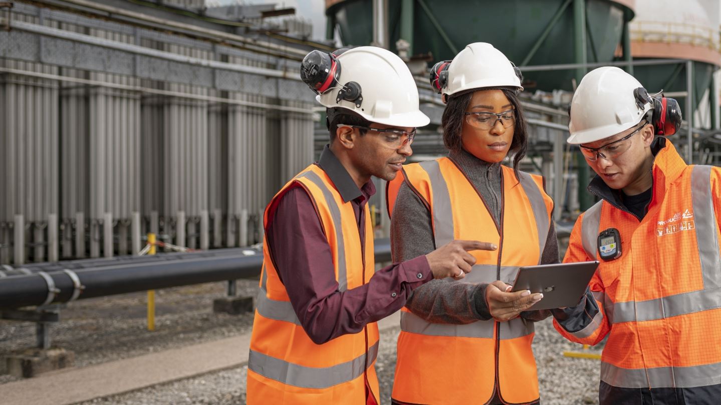 Operators and technicians conversing in front of industrial gas plant