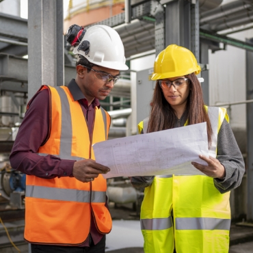 Male and female plant operators conversing at plant