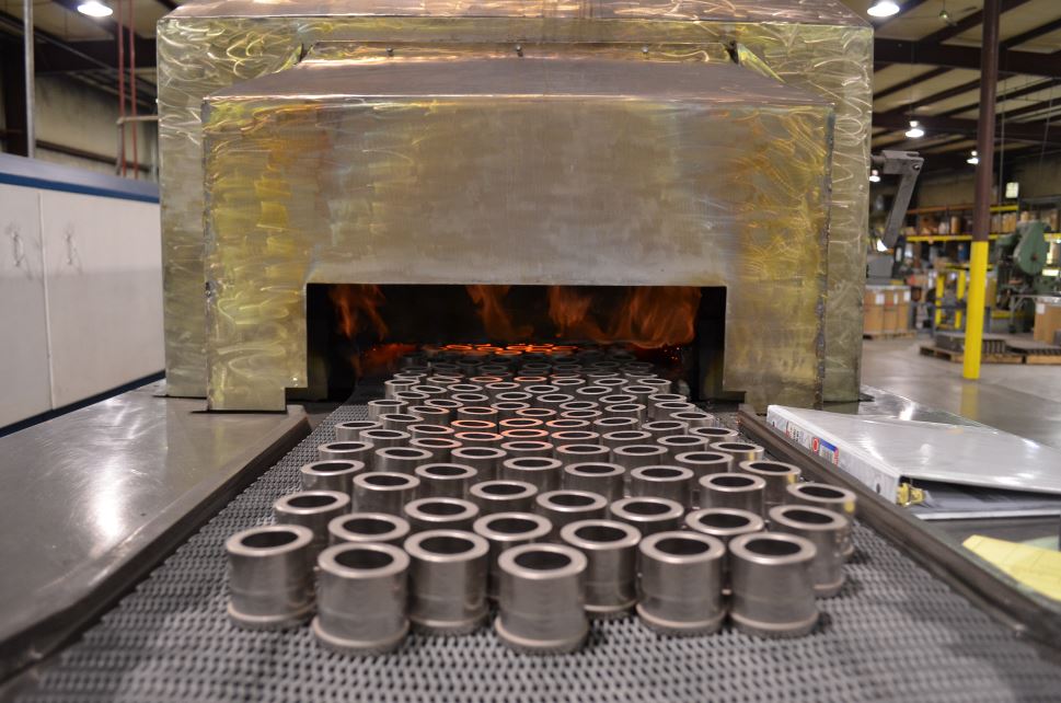 Carbon steel powdered metal parts entering a sintering furnace